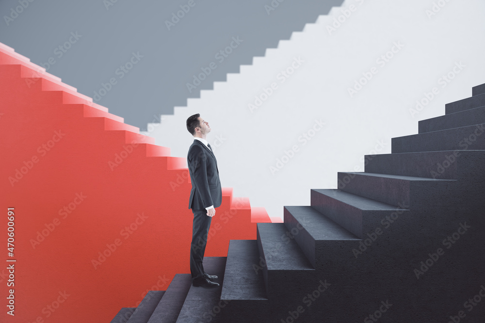 Attractive young european businessman standing on red and concrete staircase with mock up place. Suc