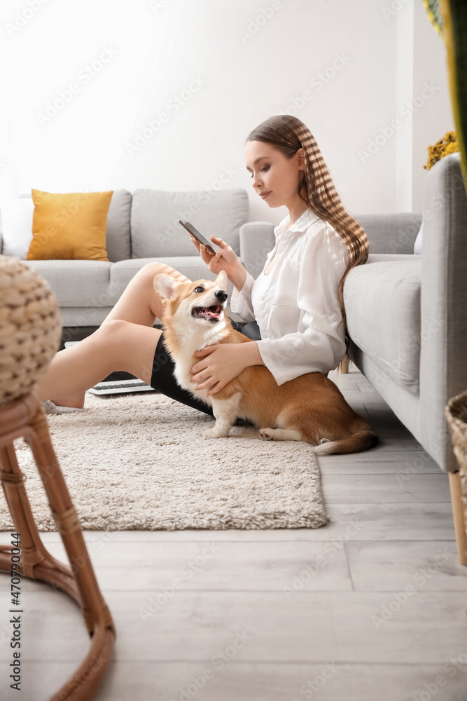 在家里用手机带着可爱的柯基犬的年轻女人