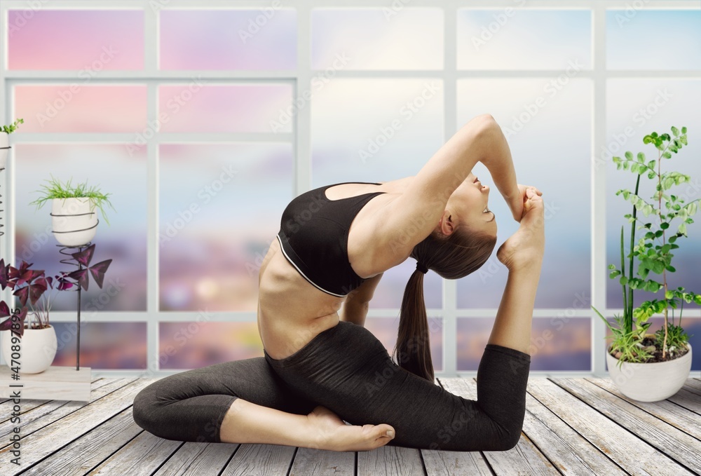 Young woman in sportswear, practicing yoga, performs an exercise