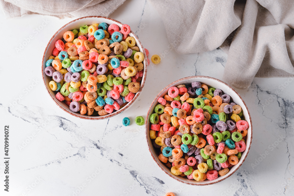 Bowls with crunchy corn flakes rings on white background