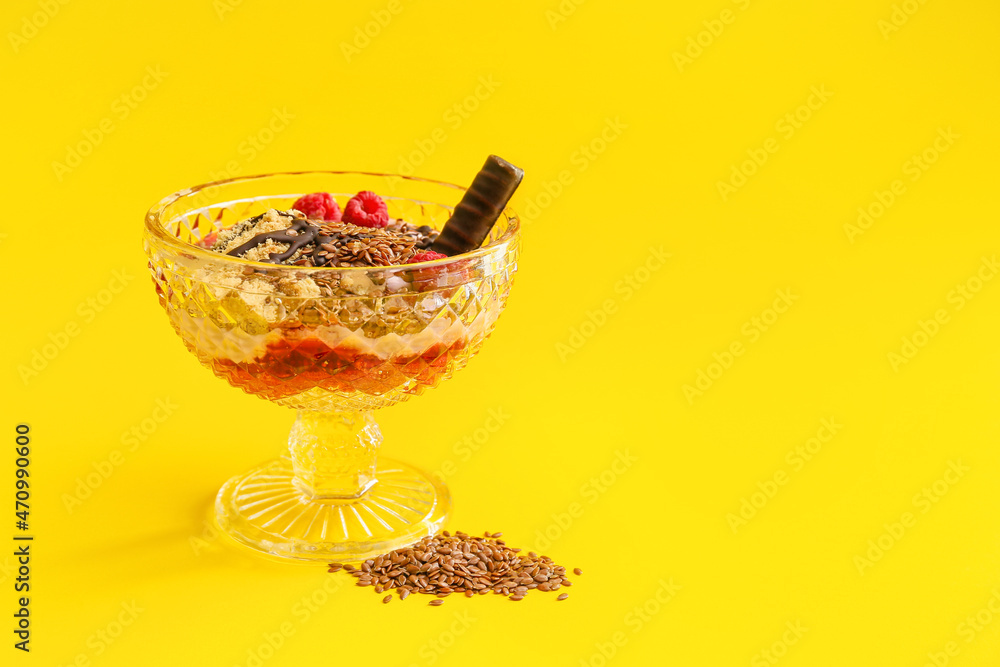 Tasty dessert with flax seeds and yoghurt in glass on color background