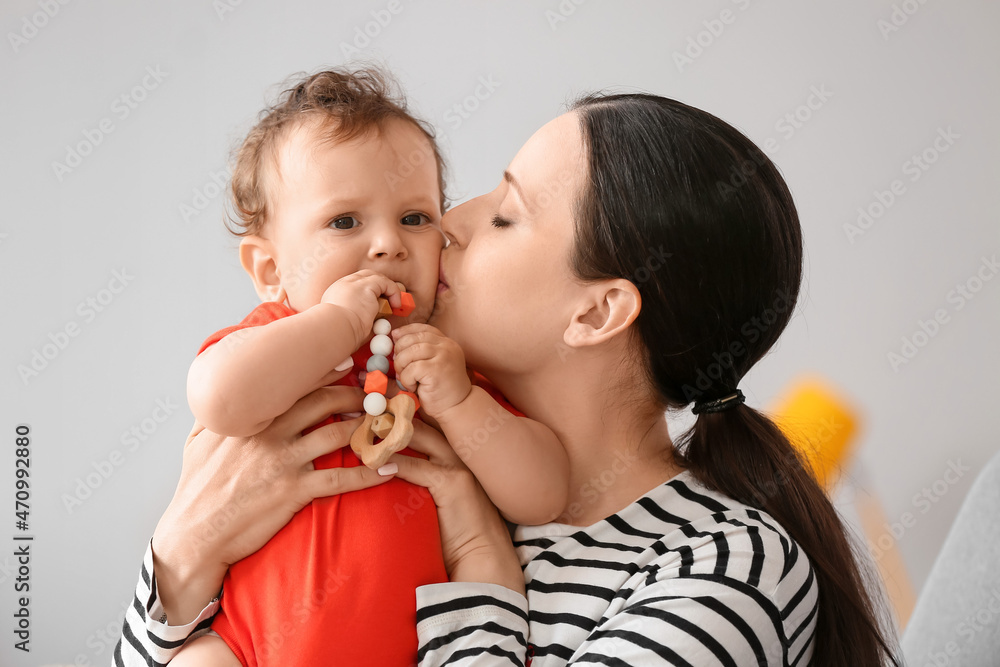 年轻妈妈在卧室里用玩具亲吻她的小宝宝