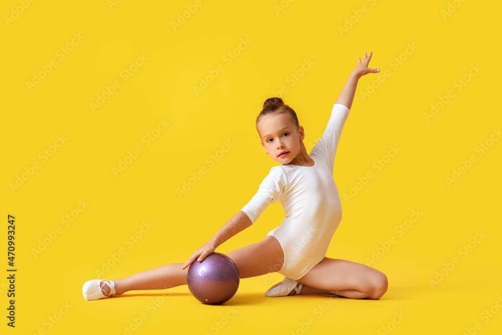 Little girl doing gymnastics with ball on color background