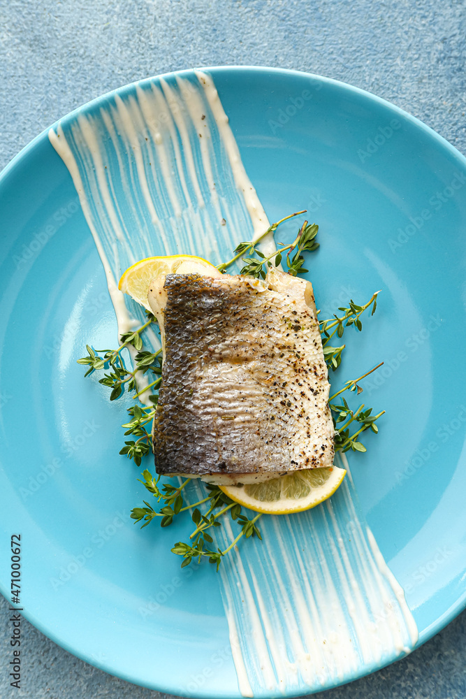 Plate of tasty sea bass fish on blue background