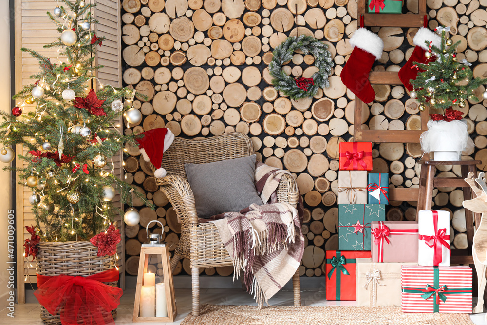 Christmas trees with armchair, ladder and gifts near wooden wall