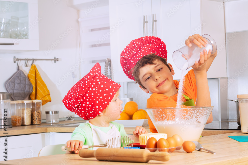 Children cook cookies adding sugar to dough mix