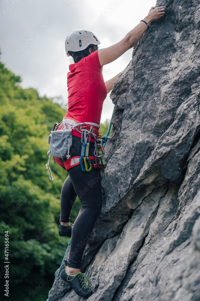 一名登山者在攀岩。女登山者在陡峭的墙壁上攀岩。冒险运动活动，肾上腺