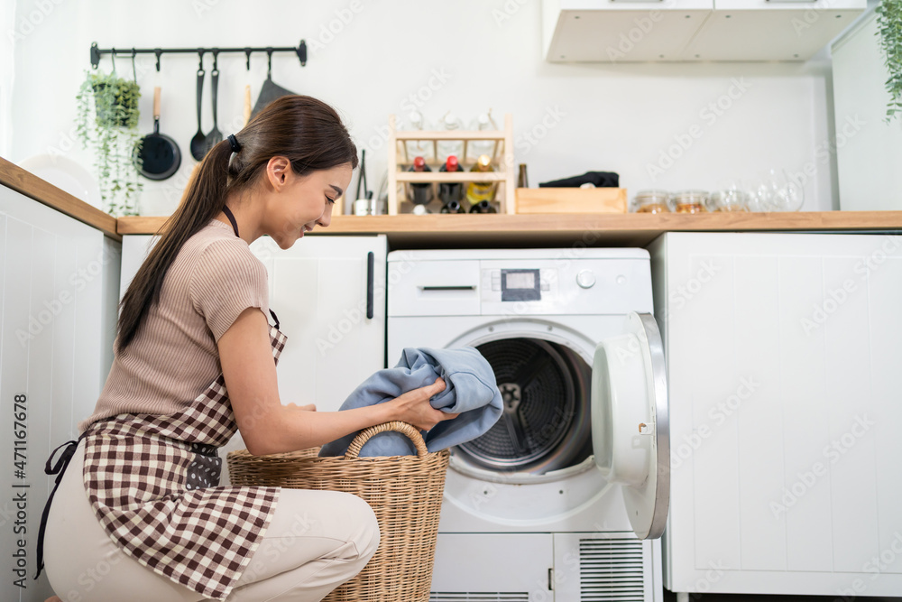 亚洲美女把脏衣服放进屋里的洗衣机里。