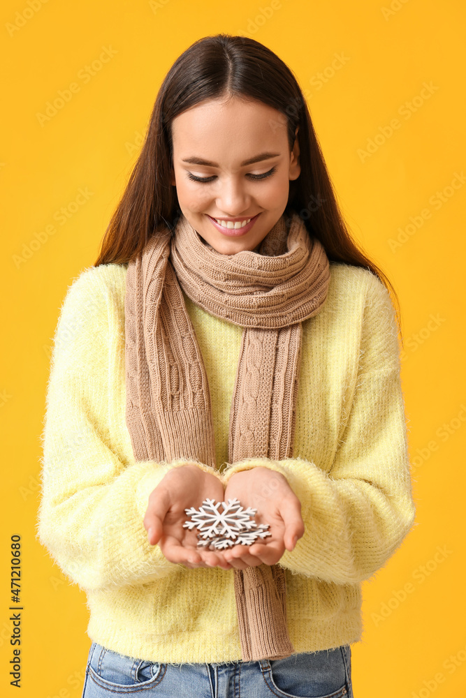 Beautiful woman in warm scarf with snowflakes on yellow background