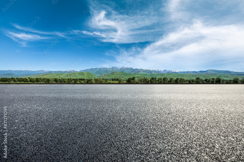 Asphalt road and green mountains under blue sky