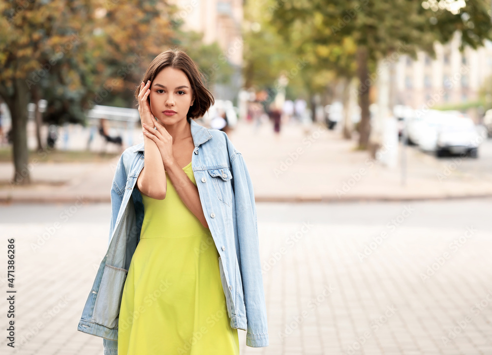 穿着连衣裙和牛仔夹克的年轻女子在户外摆姿势