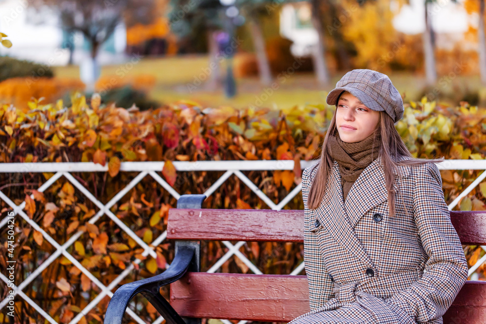 穿着时髦外套、戴着时髦帽子的年轻女性的户外秋季肖像。