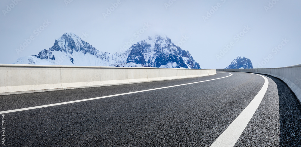 蓝天下的沥青路和雪山。公路和山脉背景。