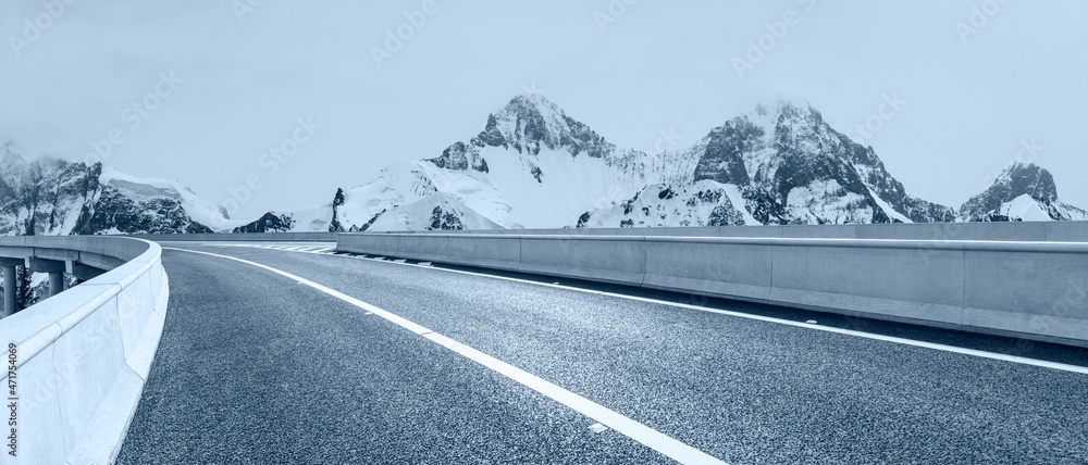 蓝天下的沥青路和雪山。公路和山脉背景。