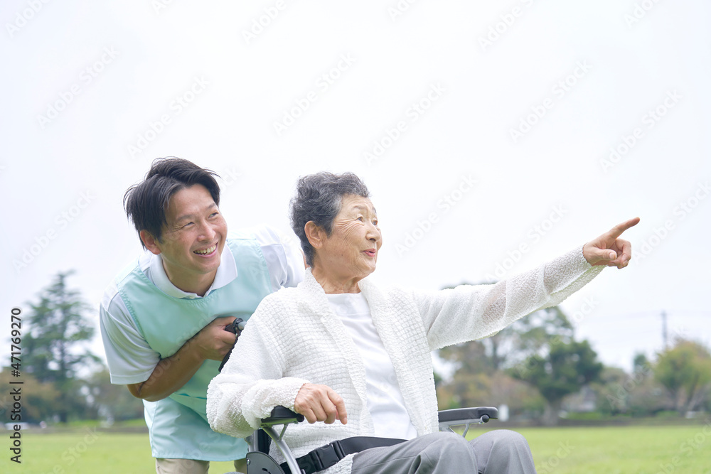 介護士と車椅子に乗る高齢者　屋外