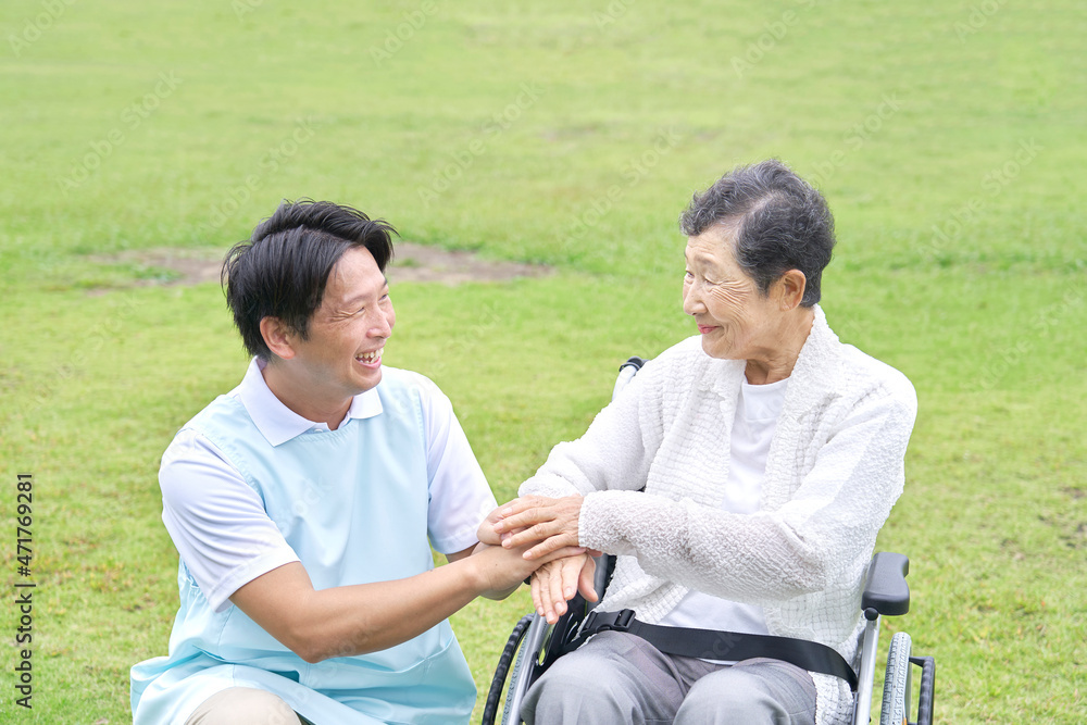 介護士と車椅子に乗る高齢者　屋外