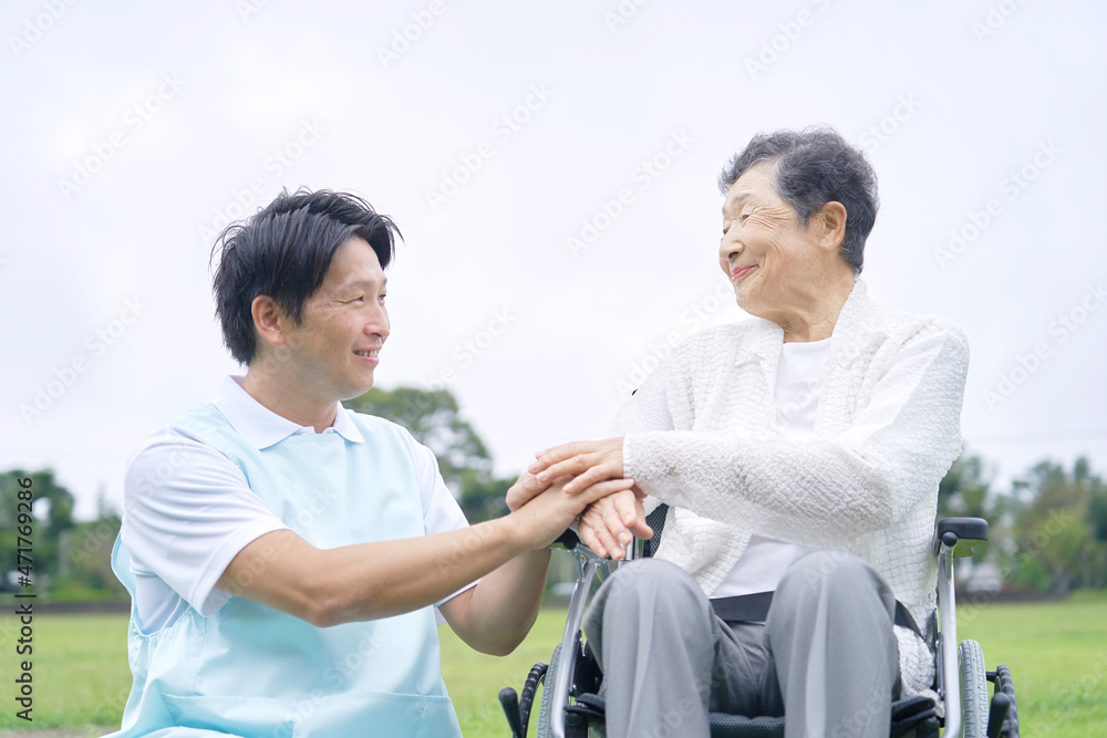 介護士と車椅子に乗る高齢者　屋外