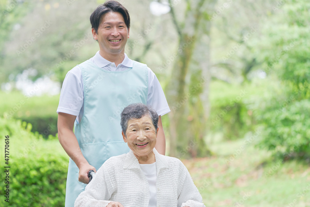 介護士と車椅子に乗る高齢者　屋外