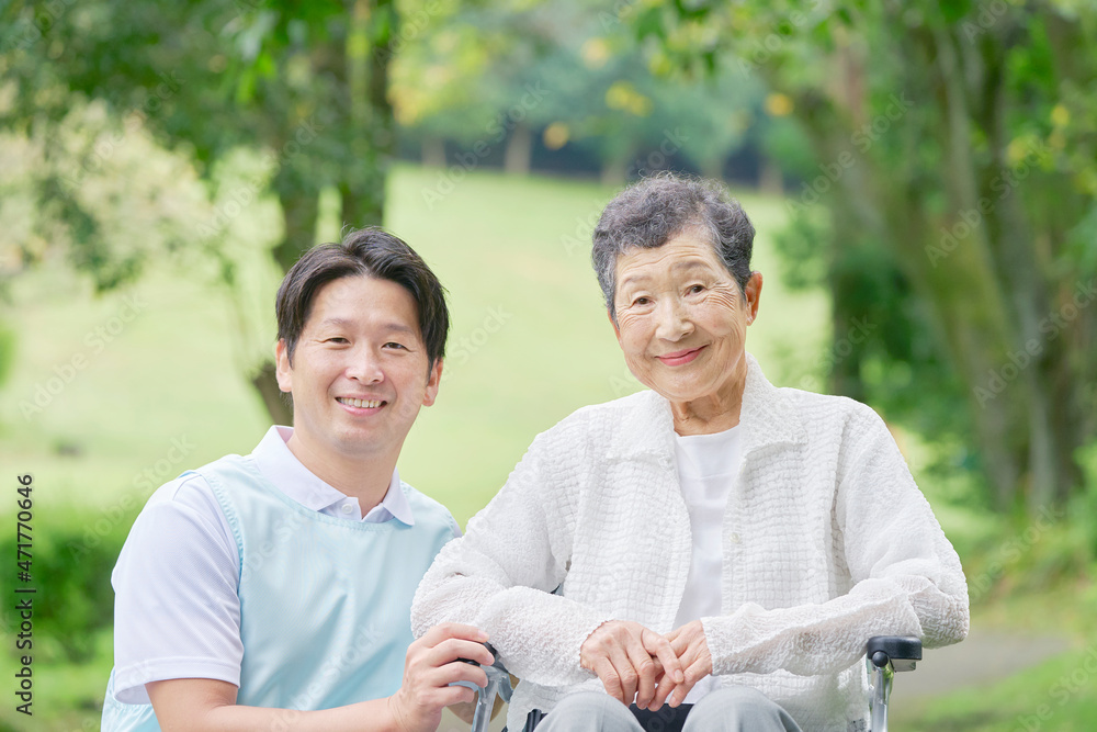 介護士と車椅子に乗る高齢者　屋外