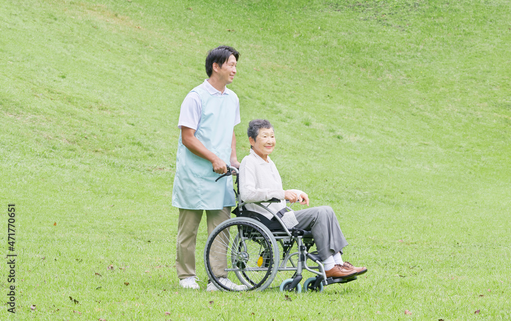 介護士と車椅子に乗る高齢者　屋外