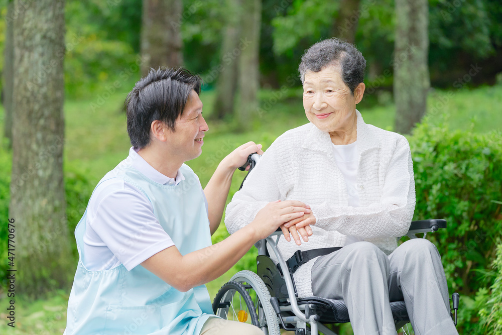 介護士と車椅子に乗る高齢者　屋外