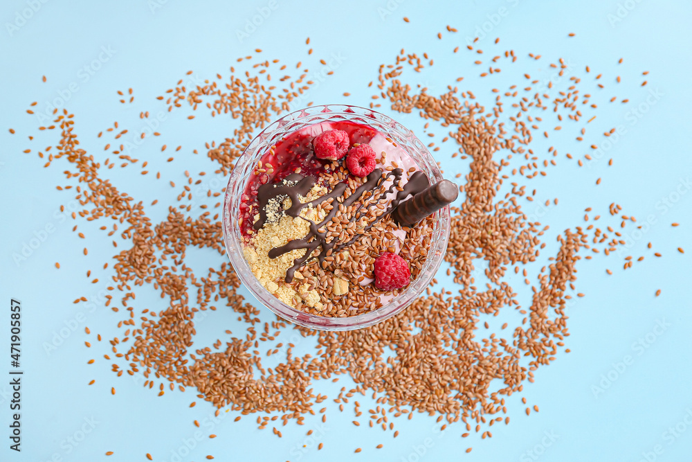 Tasty dessert with flax seeds and yoghurt in glass on color background