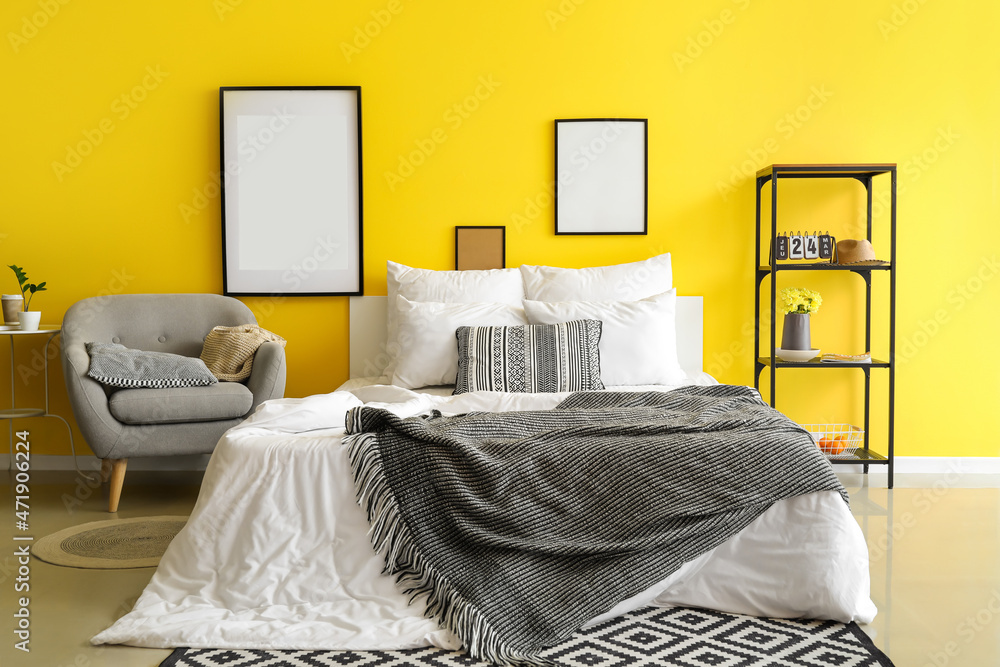 Interior of bright bedroom with blank frames and armchair