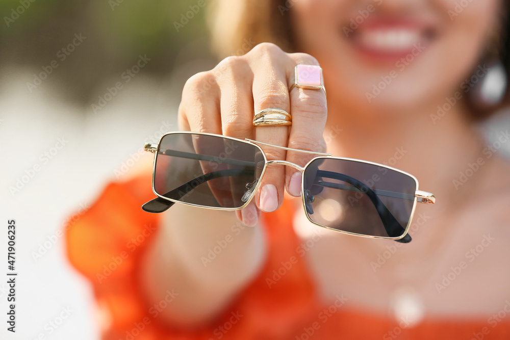 Female hand with stylish jewelry and sunglasses, closeup