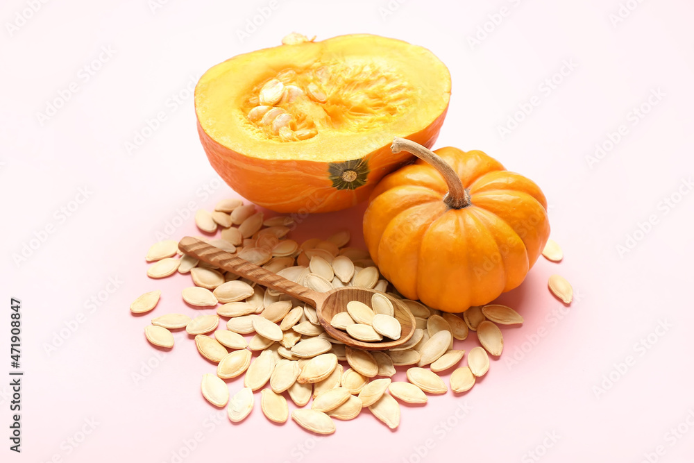 Pile of natural pumpkin seeds and fresh vegetables on light background