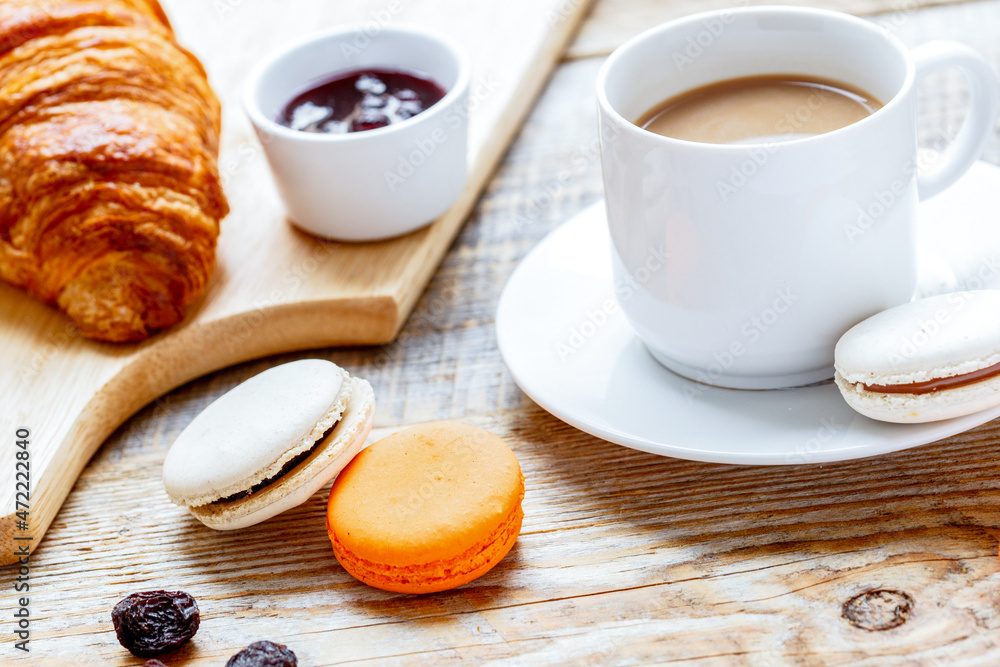 sweet breakfast with coffee, macaroons and croissants on wooden table