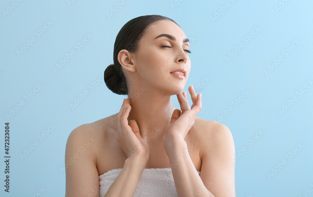 Smiling woman applying essential oil after shower on color background