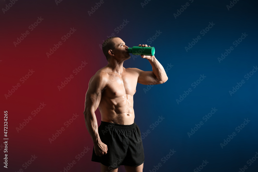 Male bodybuilder drinking protein shake on dark background