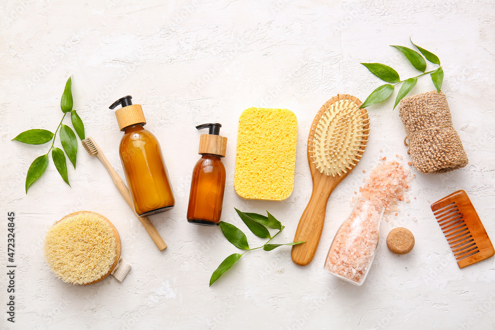 Set of bath supplies with sponges and plant branches on white background