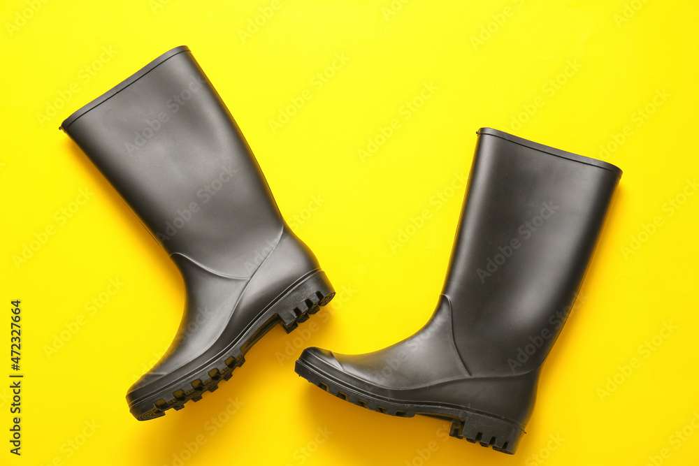 Pair of rubber boots on yellow background