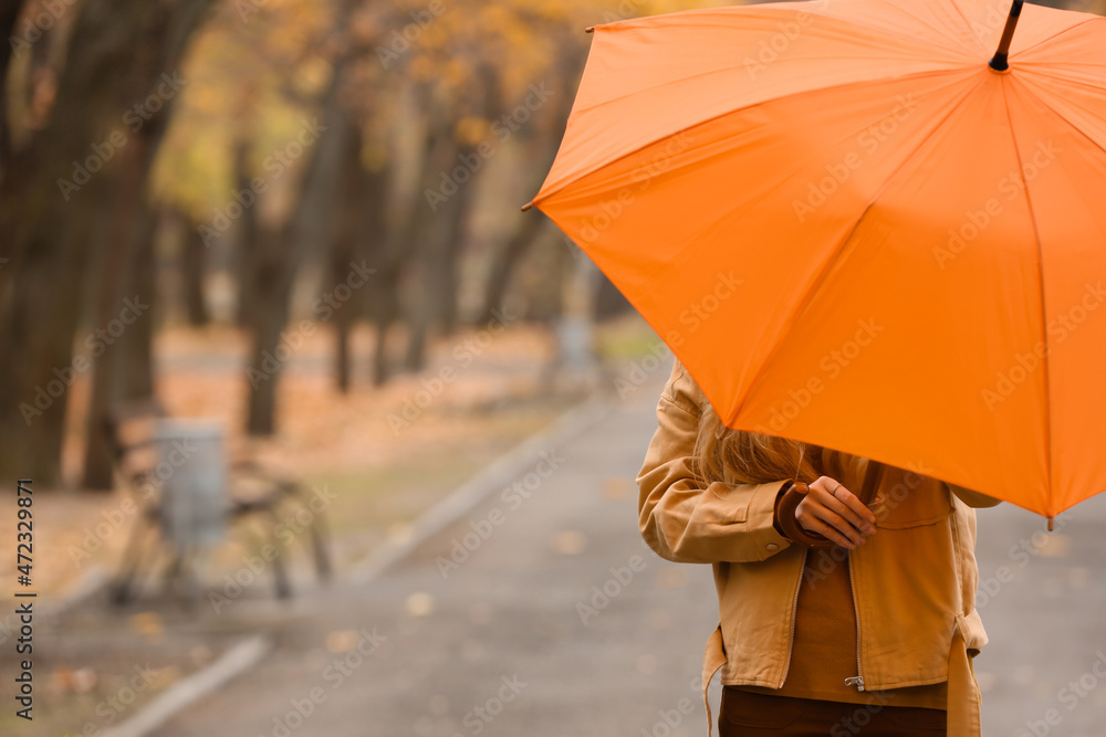 秋天公园里带着时尚明亮雨伞的女人