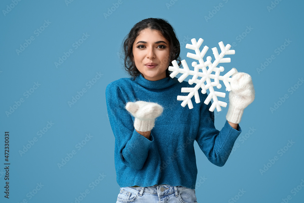 年轻女子手持大雪花，在蓝色背景上飞吻