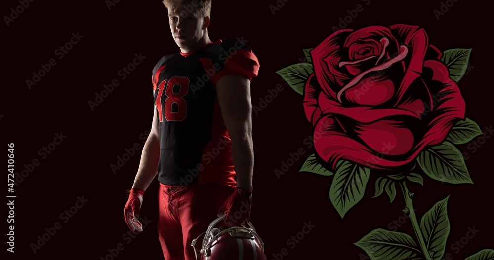 Portrait of confident male american footballer holding helmet by rose against black background