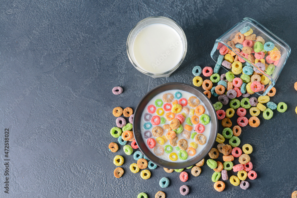 Crunchy corn flakes rings with milk on dark background