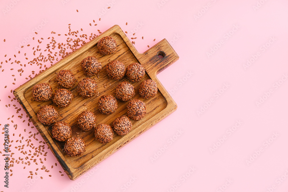 Board with tasty flax seed candies on color background