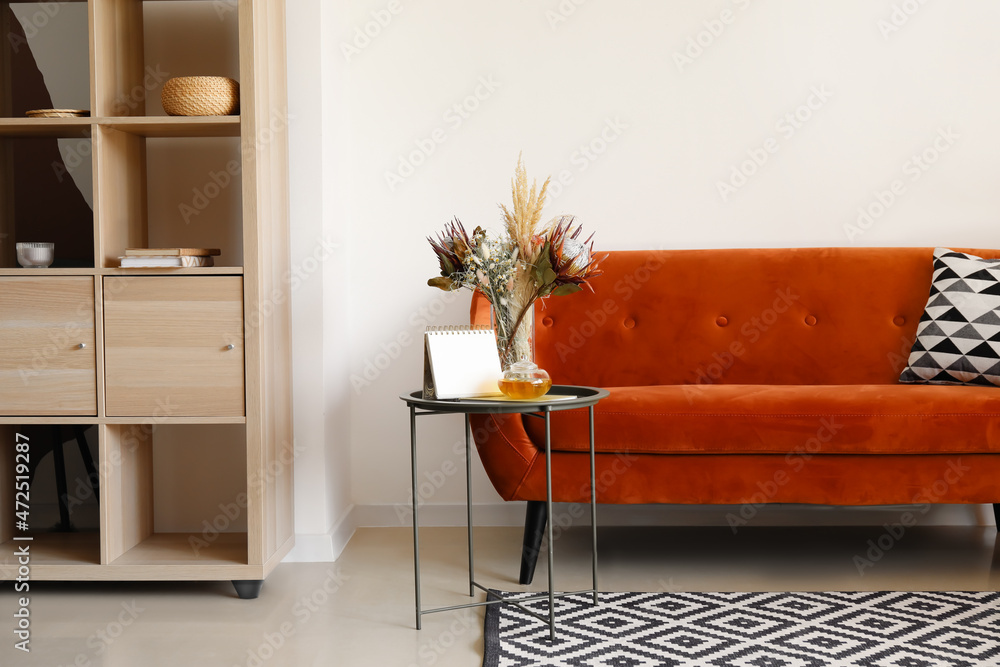 Interior of living room with red sofa and dried flowers in vase