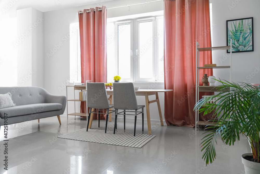 Interior of dining room with table, shelving units and red curtains