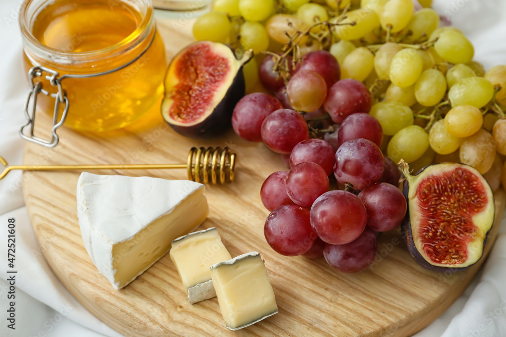 Wooden board with ripe grapes, fig, cheese and honey, closeup