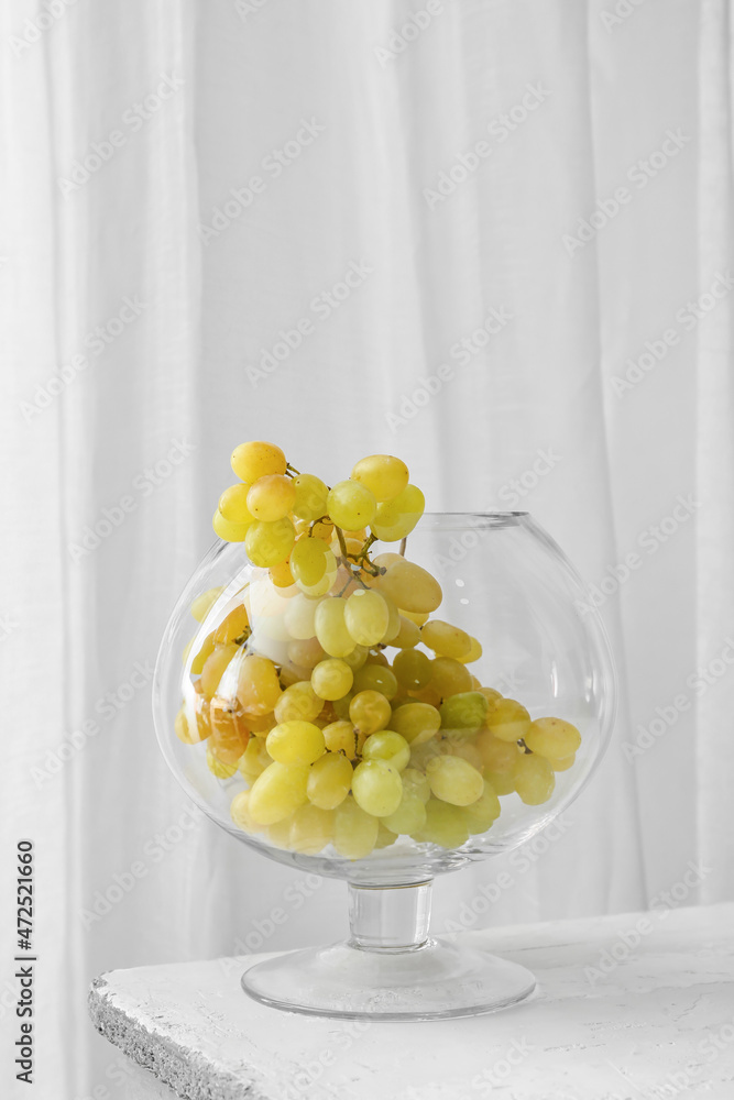 Glass with sweet grapes on table in room