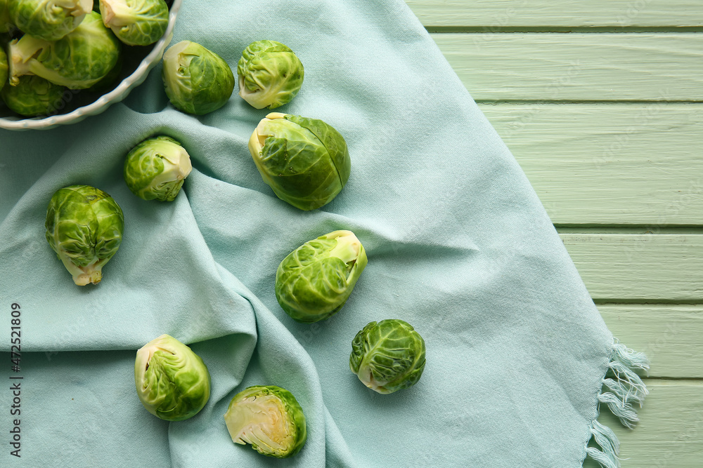 Bowl with fresh raw Brussels cabbage on color wooden background