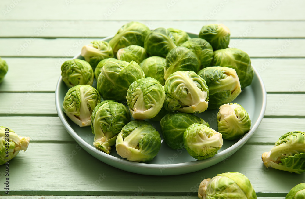 Plate with fresh raw Brussels cabbage on color wooden background