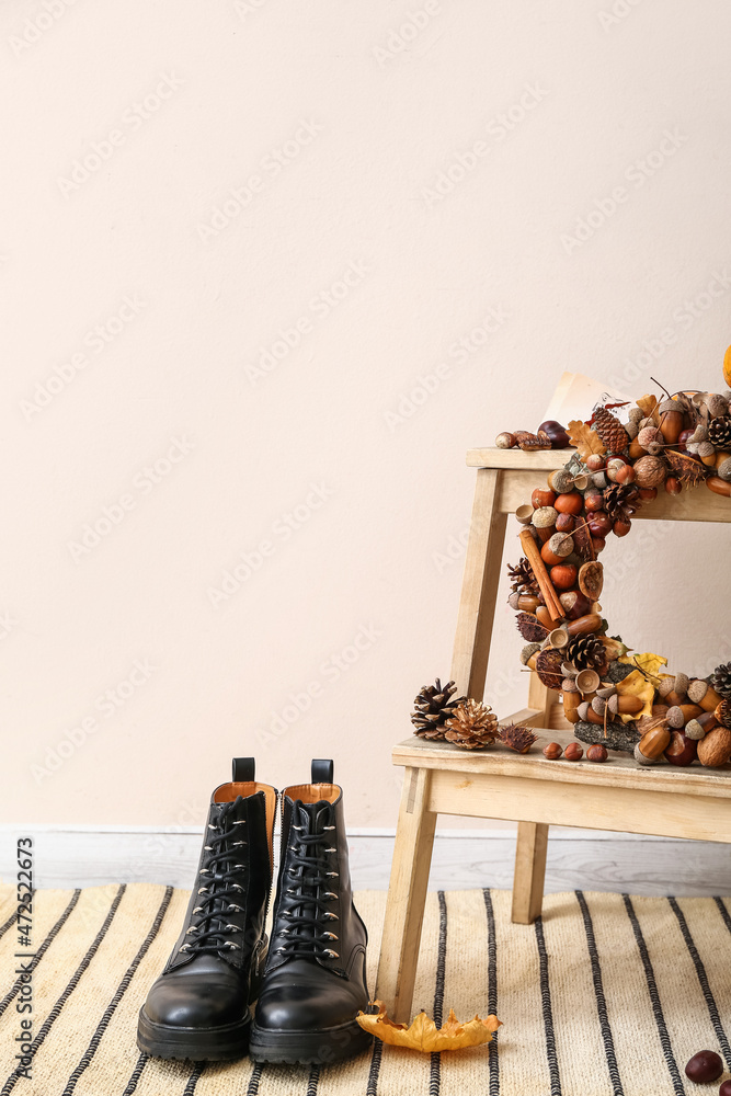 Beautiful acorn wreath on step ladder and boots near light wall