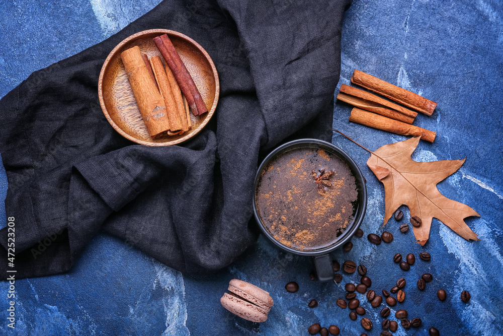 Cup of tasty coffee with cinnamon on blue background