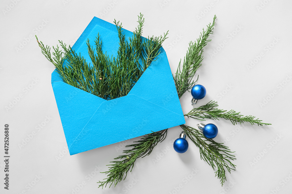 Composition with envelope, coniferous branches and Christmas decorations on white background