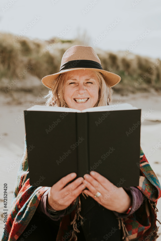 Happy senior woman reading her book outdoors