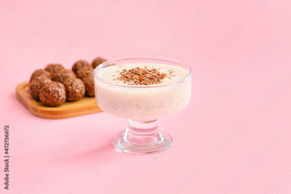 Tasty dessert with flax seeds and yoghurt in glass on color background